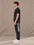 Model wearing SM Motion Stripe Track Trousers in Midnight Black, side view.