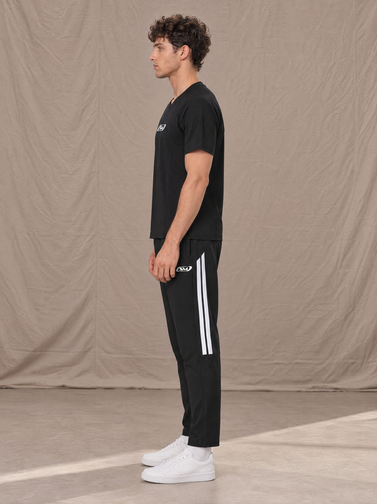 Model wearing SM Motion Stripe Track Trousers in Midnight Black, side view.