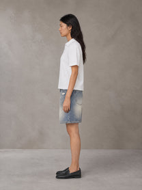 Model wearing SM Heritage Distressed Denim Shorts in Cadet Grey, side view.