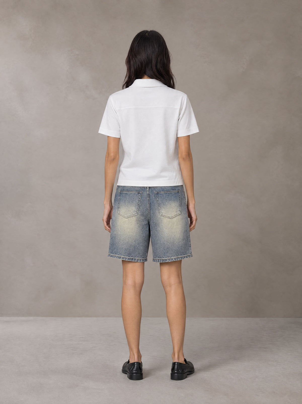 Model wearing SM Heritage Distressed Denim Shorts in Cadet Grey, rear view.