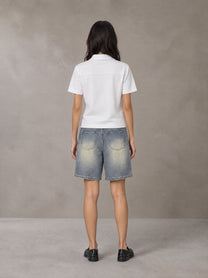 Model wearing SM Heritage Distressed Denim Shorts in Cadet Grey, rear view.
