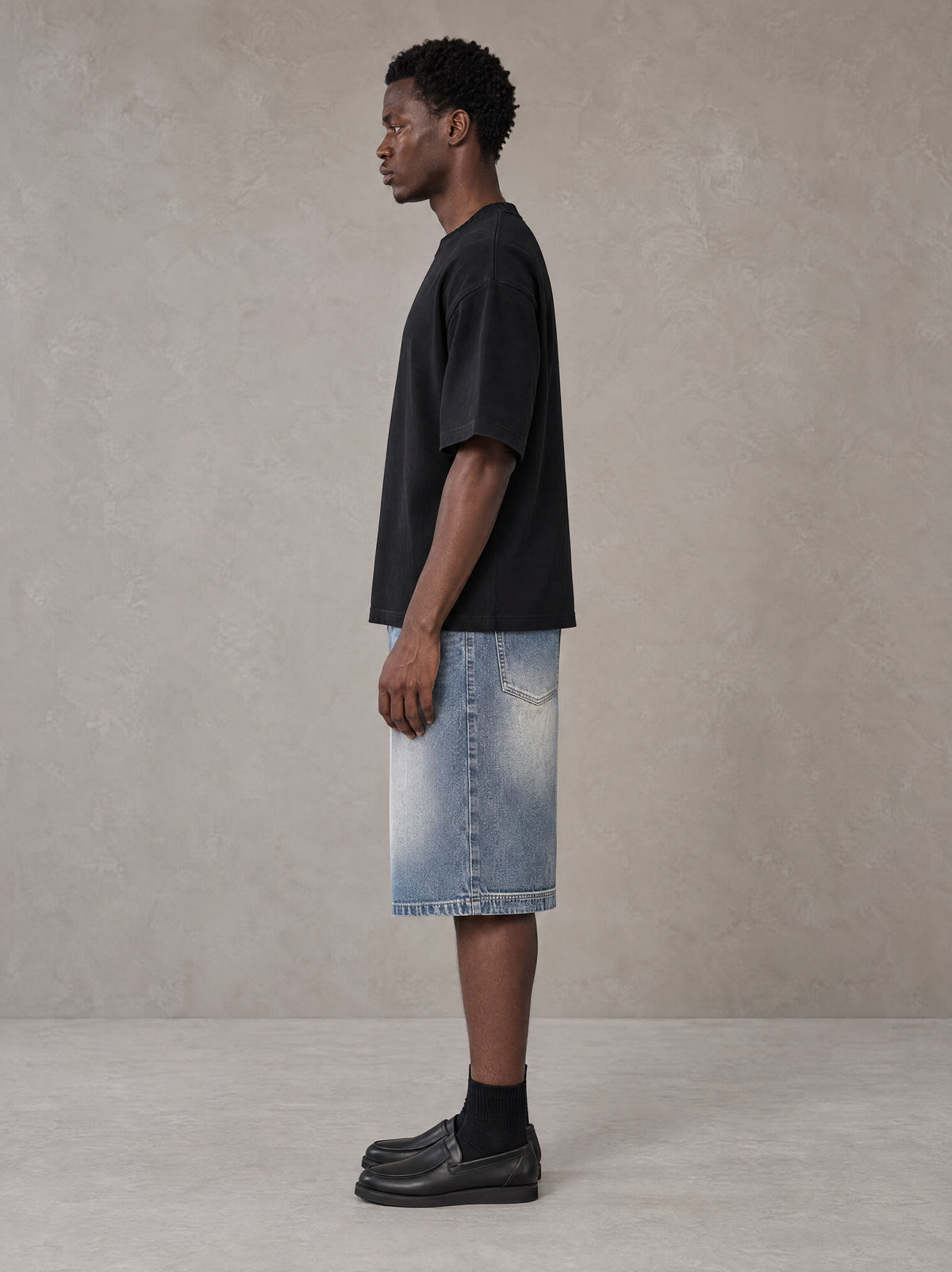 Model wearing SM Heritage Vintage Wash Denim Shorts in Cadet Grey, side view.