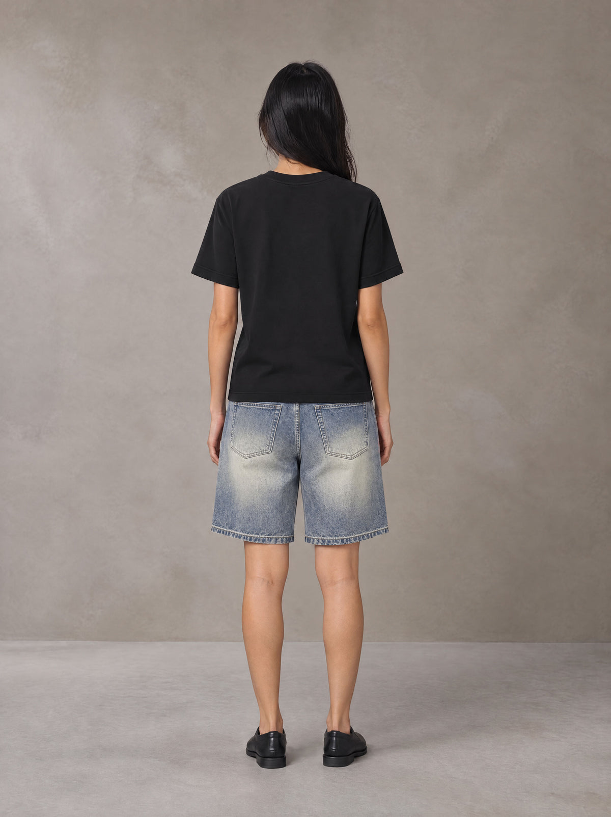 Model wearing SM Sunwash T-shirt in Midnight Black, rear view.