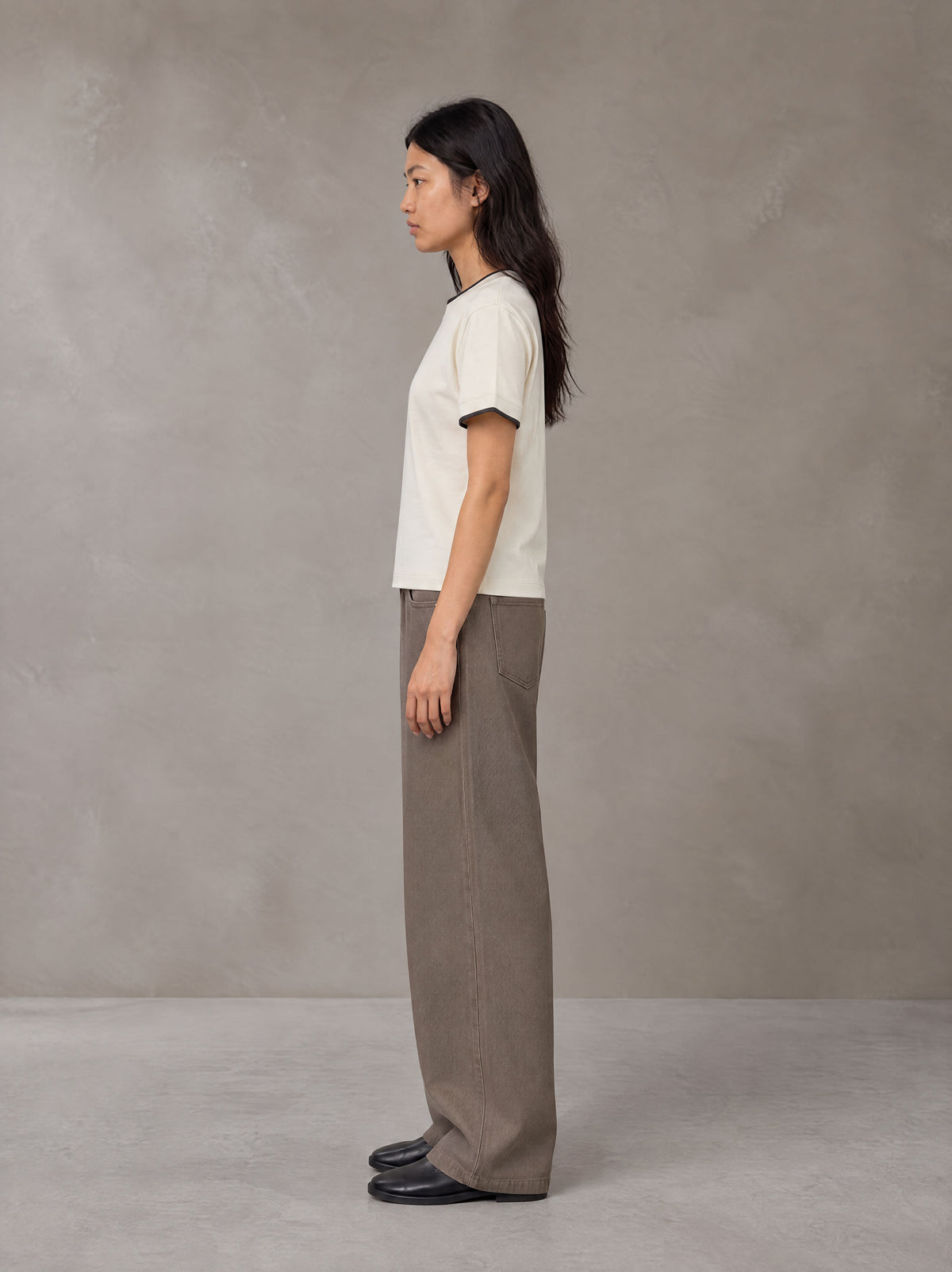Model wearing SM Sunwash T-shirt in Oat Grey, side view.