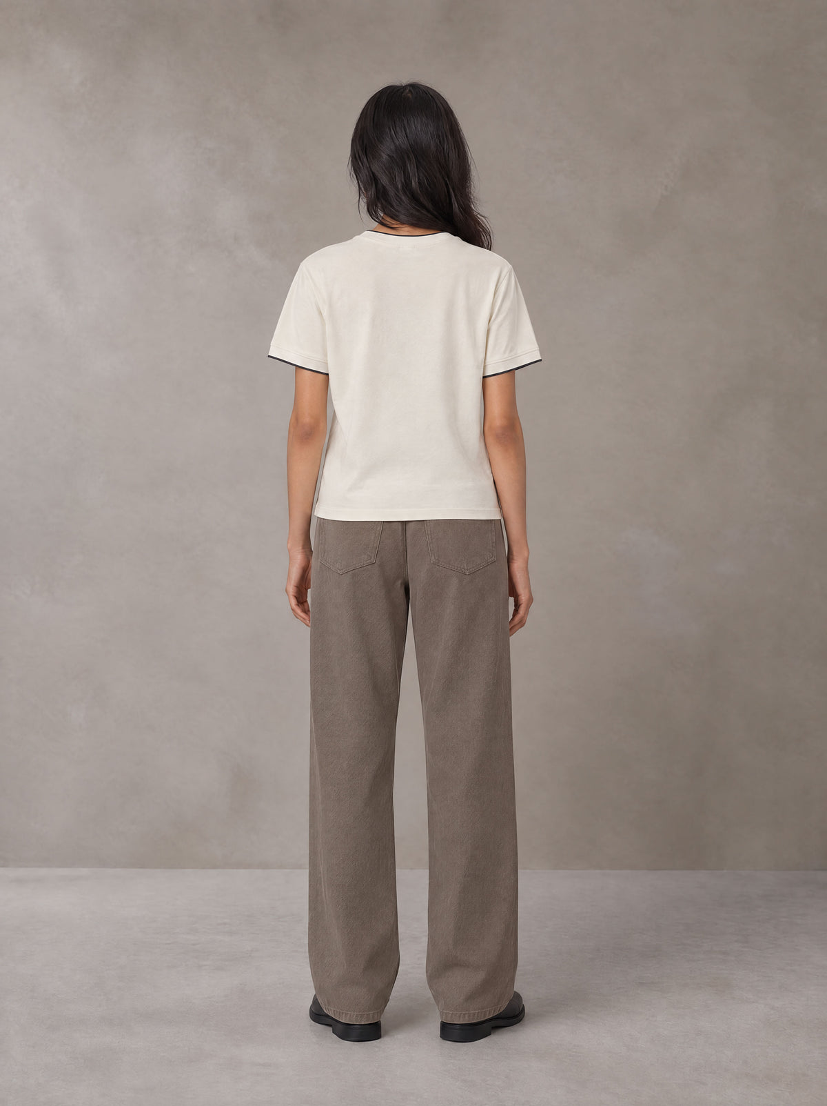 Model wearing SM Sunwash T-shirt in Oat Grey, rear view.