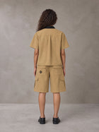 Model wearing SM Eternal Fleur Shirt in Camel Tan with SM Eternal Fleur Utility Shorts in Camel Tan, rear view.