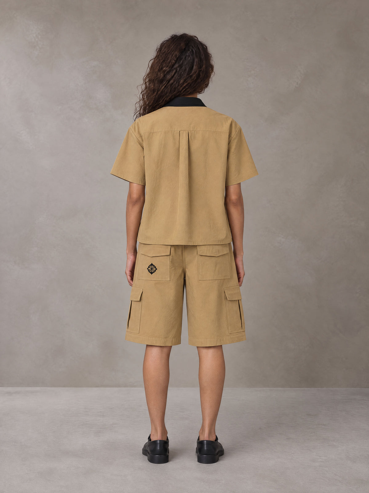 Model wearing SM Eternal Fleur Shirt in Camel Tan with SM Eternal Fleur Utility Shorts in Camel Tan, rear view.