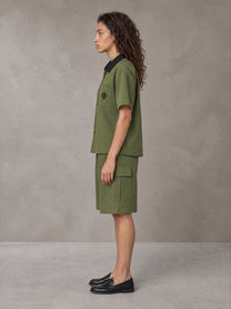 Model wearing SM Eternal Fleur Shirt in Camo Green with SM Eternal Fleur Utility Shorts in Camo Green, side view.