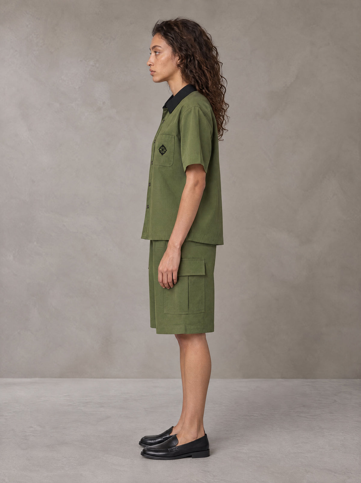 Model wearing SM Eternal Fleur Shirt in Camo Green with SM Eternal Fleur Utility Shorts in Camo Green, side view.