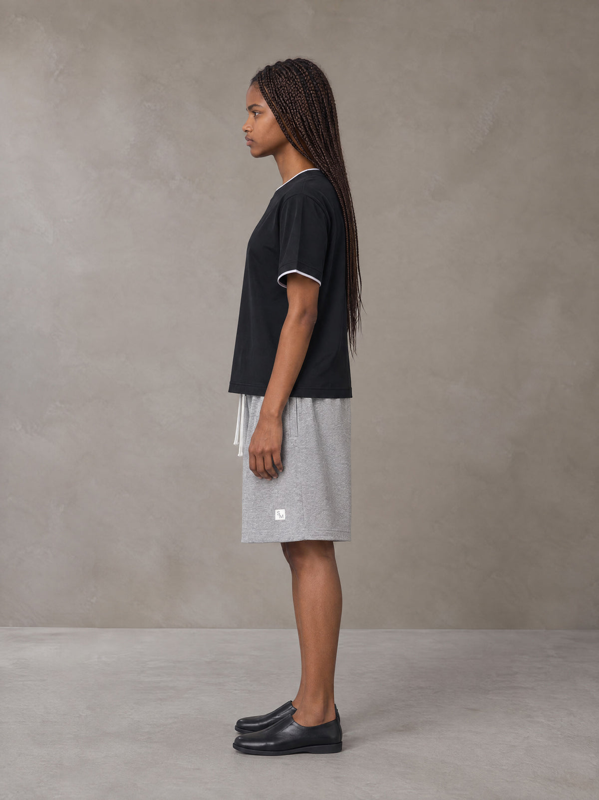 Model wearing SM Plaid Shorts in Floral Grey, side view.