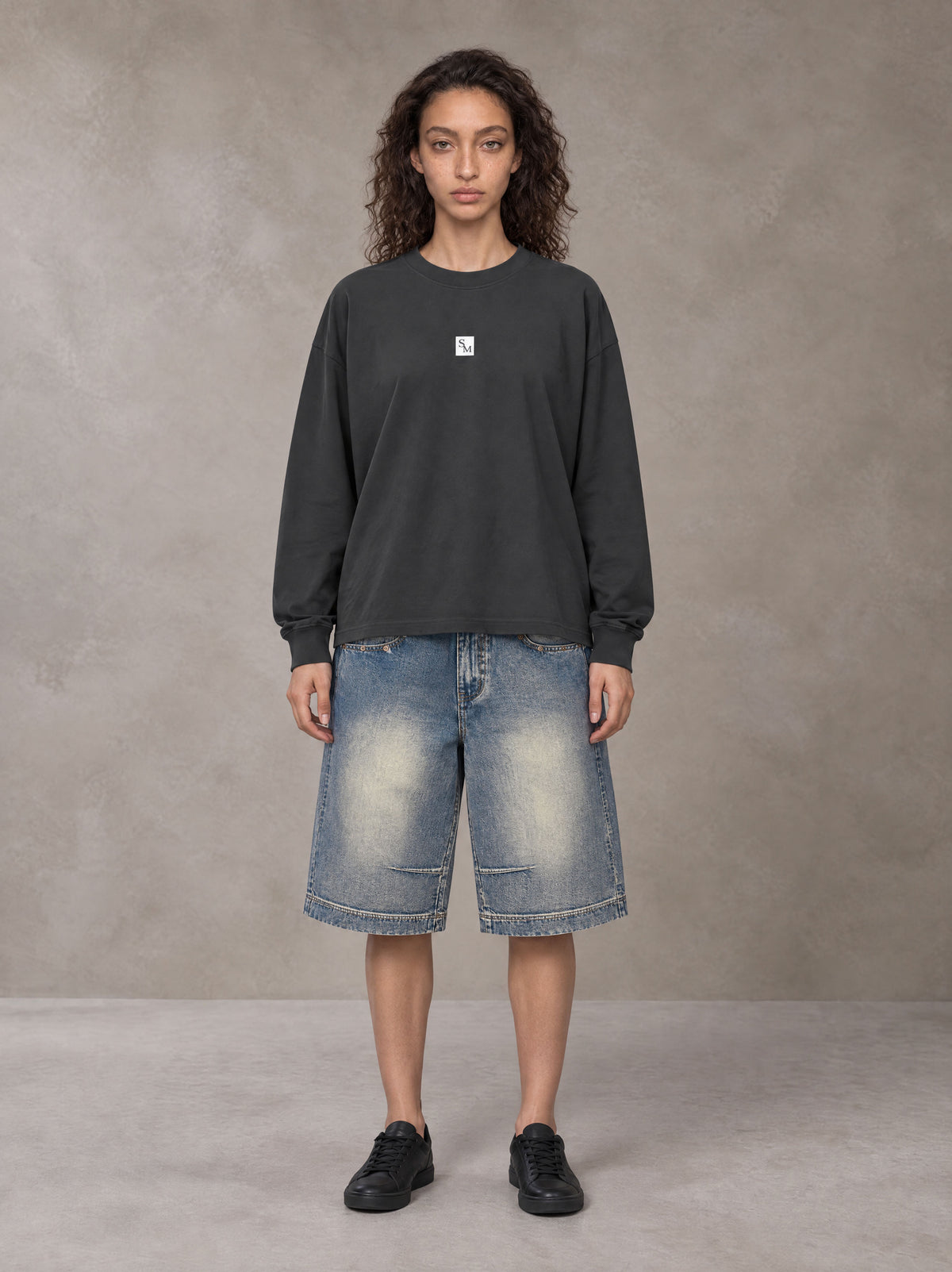 Model wearing SM Sig. Long Sleeve T-shirt in Deep Charcoal, front view.