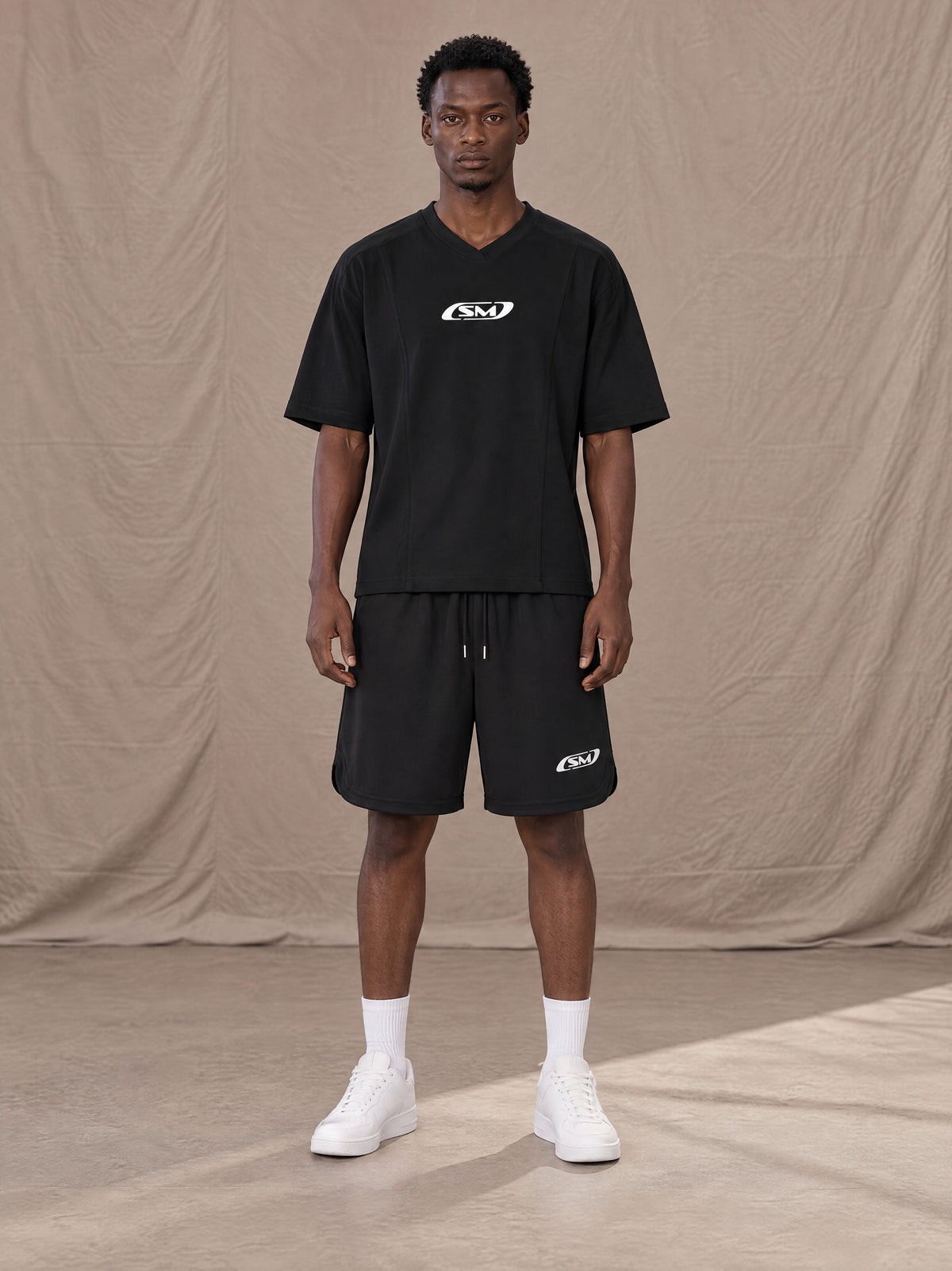 Model wearing SM Motion T-shirt in Midnight Black with SM Motion Oversized Court Shorts in Midnight Black, front view.