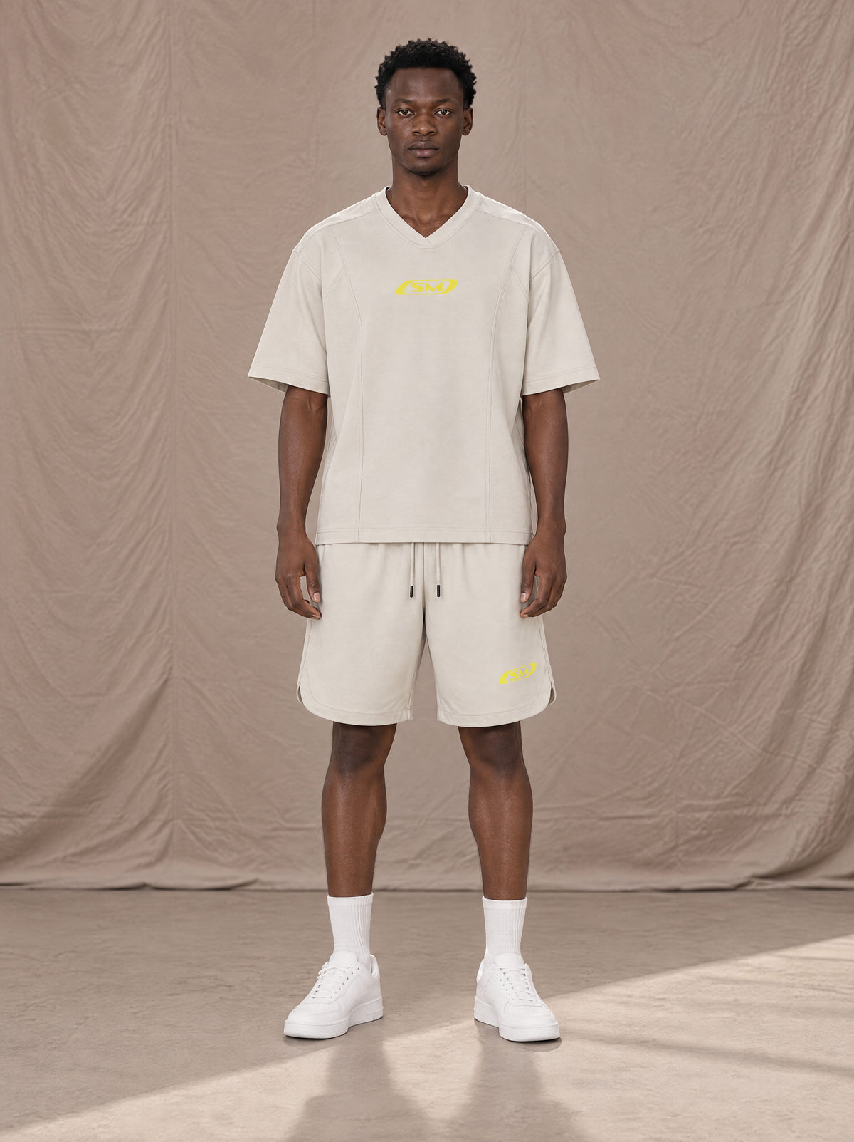 Model wearing SM Motion T-shirt in Oat Grey with SM Motion Oversized Court Shorts in Oat Grey, front view.