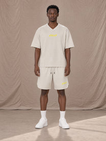 Model wearing SM Motion T-shirt in Oat Grey with SM Motion Oversized Court Shorts in Oat Grey, front view.