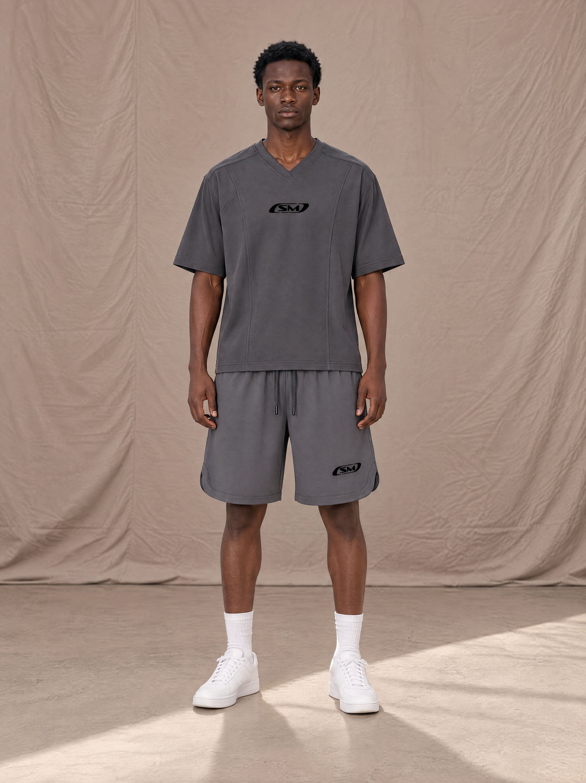 Model wearing SM Motion T-shirt in Deep Charcoal with SM Motion Oversized Court Shorts in Deep Charcoal, front view.