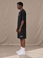 Model wearing SM Motion T-shirt in Midnight Black with SM Motion Oversized Court Shorts in Midnight Black, side view.