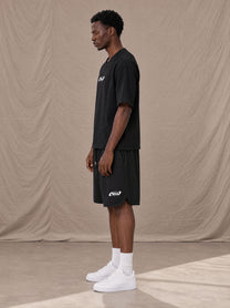 Model wearing SM Motion T-shirt in Midnight Black with SM Motion Oversized Court Shorts in Midnight Black, side view.