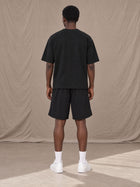 Model wearing SM Motion T-shirt in Midnight Black with SM Motion Oversized Court Shorts in Midnight Black, rear view.