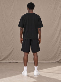 Model wearing SM Motion T-shirt in Midnight Black with SM Motion Oversized Court Shorts in Midnight Black, rear view.
