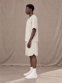 Model wearing SM Motion T-shirt in Oat Grey with SM Motion Oversized Court Shorts in Oat Grey, side view.