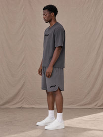 Model wearing SM Motion T-shirt in Deep Charcoal with SM Motion Oversized Court Shorts in Deep Charcoal, side view.