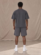 Model wearing SM Motion T-shirt in Deep Charcoal with SM Motion Oversized Court Shorts in Deep Charcoal, rear view.