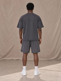 Model wearing SM Motion T-shirt in Deep Charcoal with SM Motion Oversized Court Shorts in Deep Charcoal, rear view.