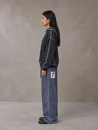 Model wearing SM Acid Wash Trousers in Deep Denim, side view.