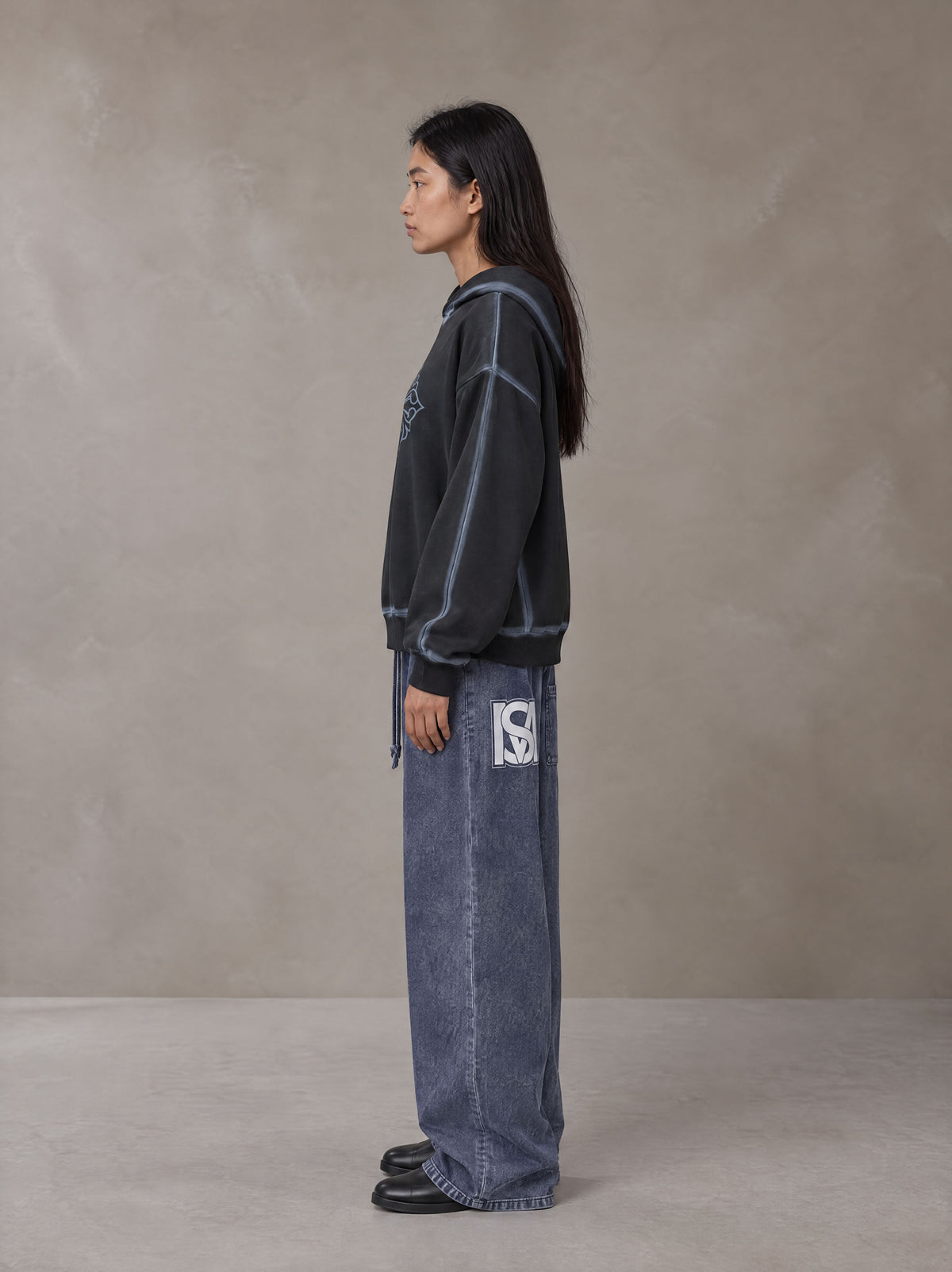 Model wearing SM Acid Wash Trousers in Deep Denim, side view.