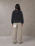 Model wearing SM Acid Wash Trousers in Stone Grey, rear view.