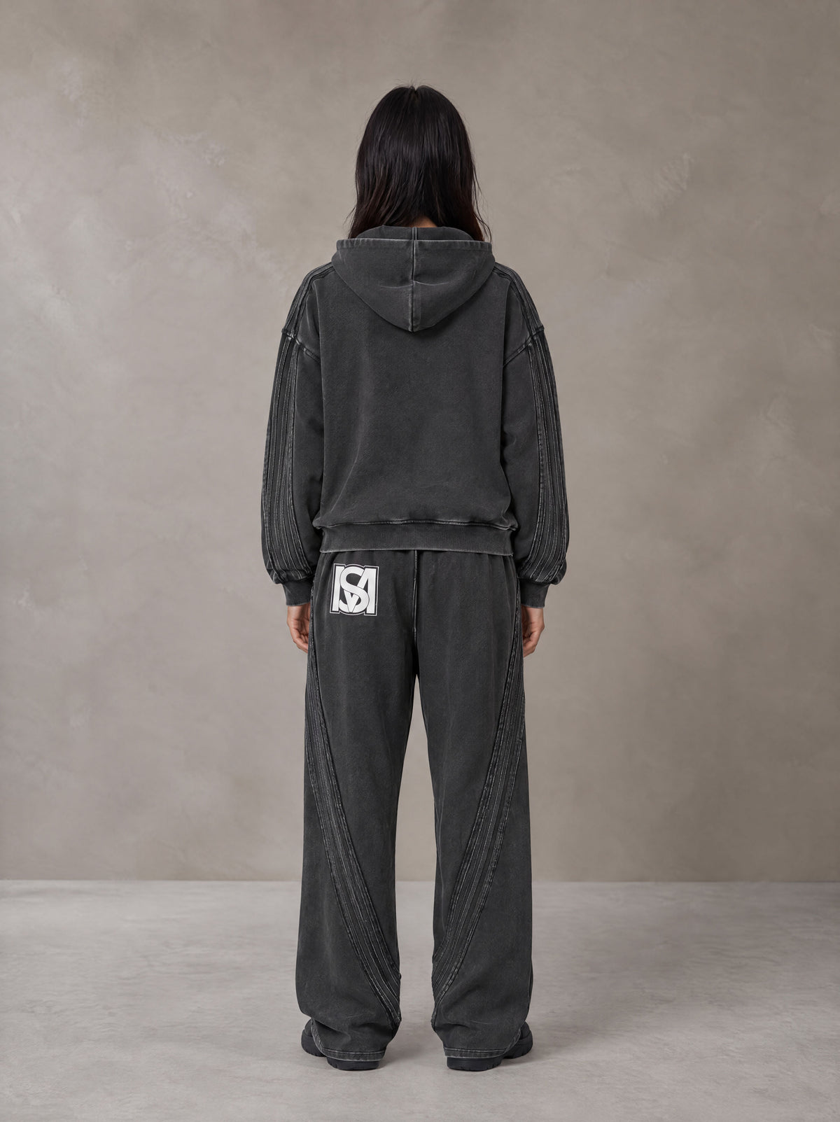 Model wearing the SM Arc Hoodie and SM Arc Sweatpants in Midnight Black, rear view.