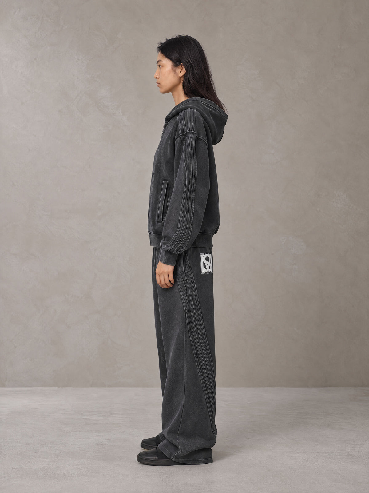 Model wearing the SM Arc Hoodie and SM Arc Sweatpants in Midnight Black, side profile.