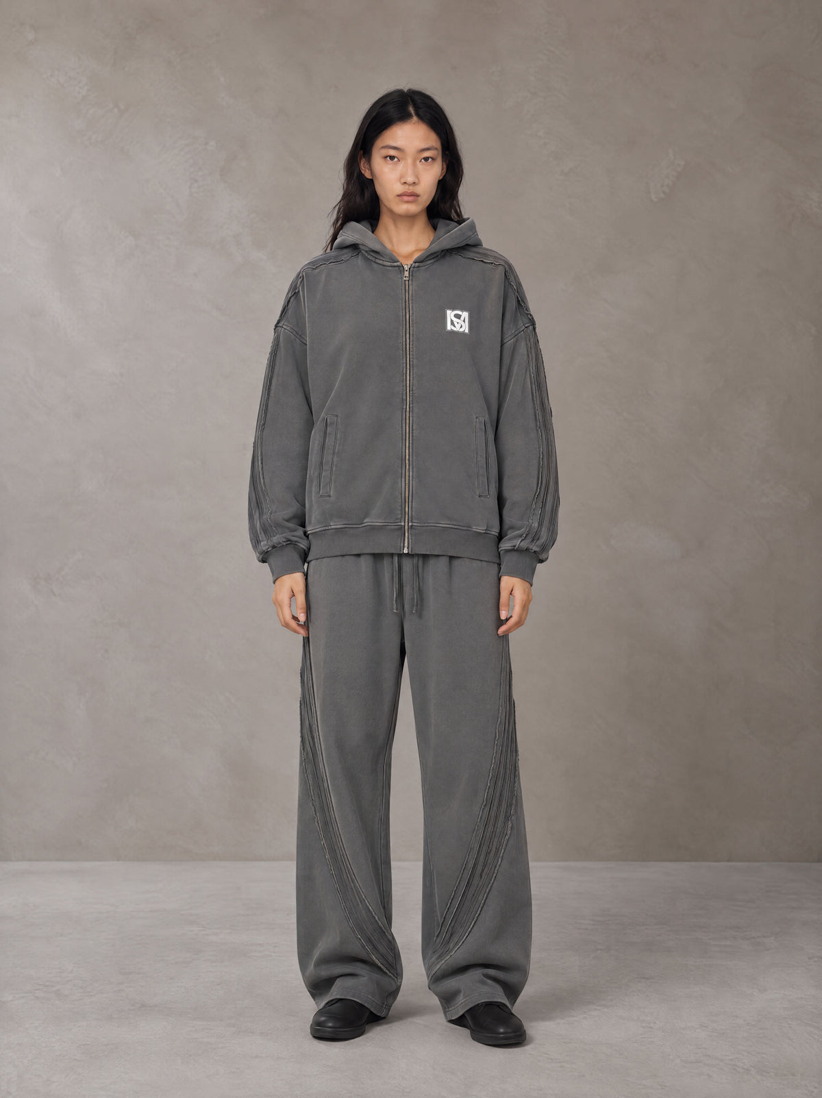 Model wearing the SM Arc Hoodie and SM Arc Sweatpants in Deep Charcoal, front view.