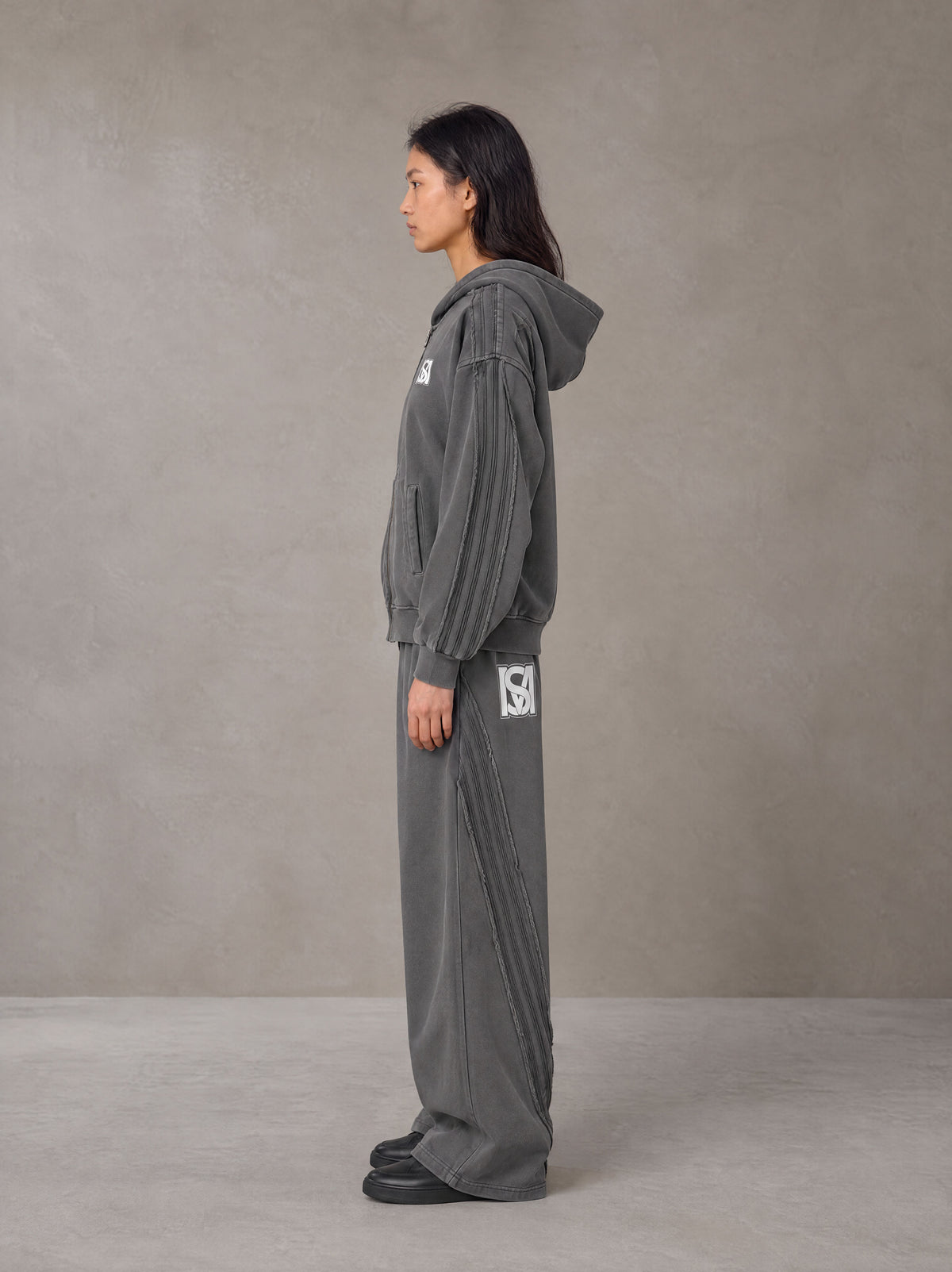 Model wearing the SM Arc Hoodie and SM Arc Sweatpants in Deep Charcoal, side profile.
