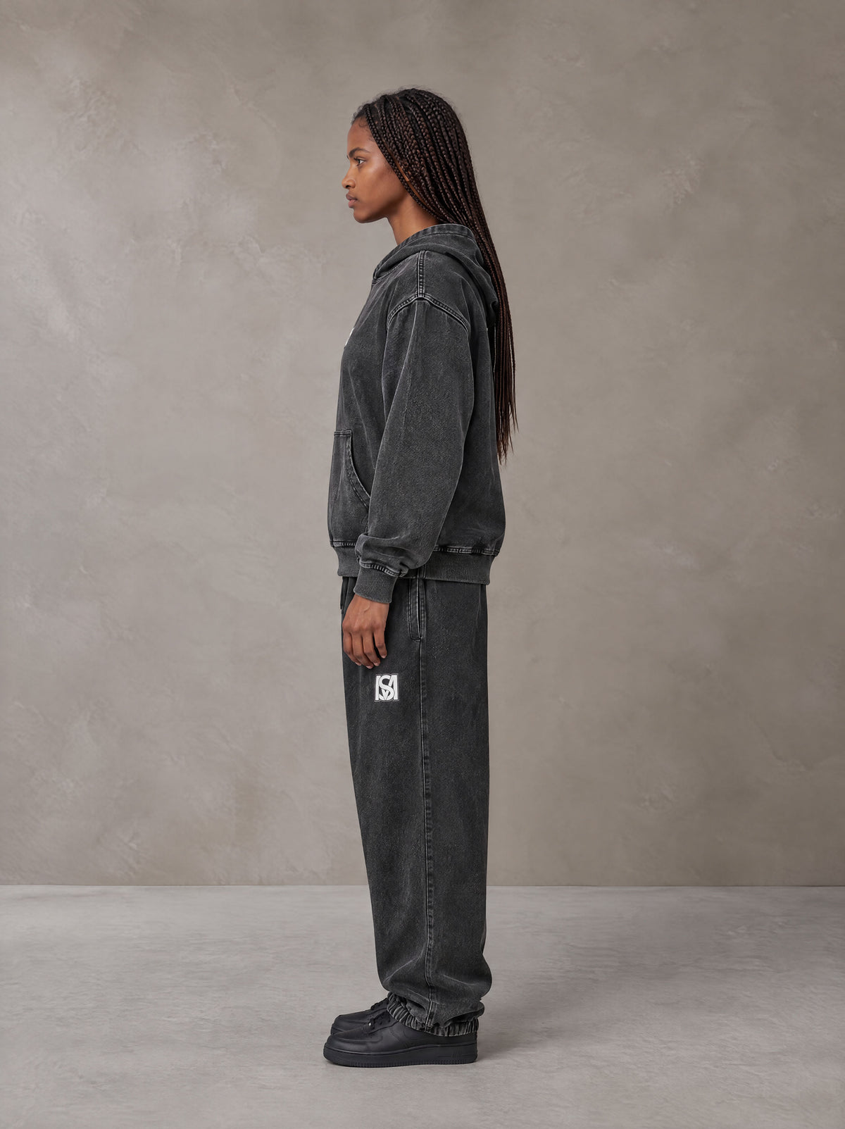 Model wearing the SM Denim Wash Hoodie and SM Denim Wash Sweatpants in Midnight Black, side profile.