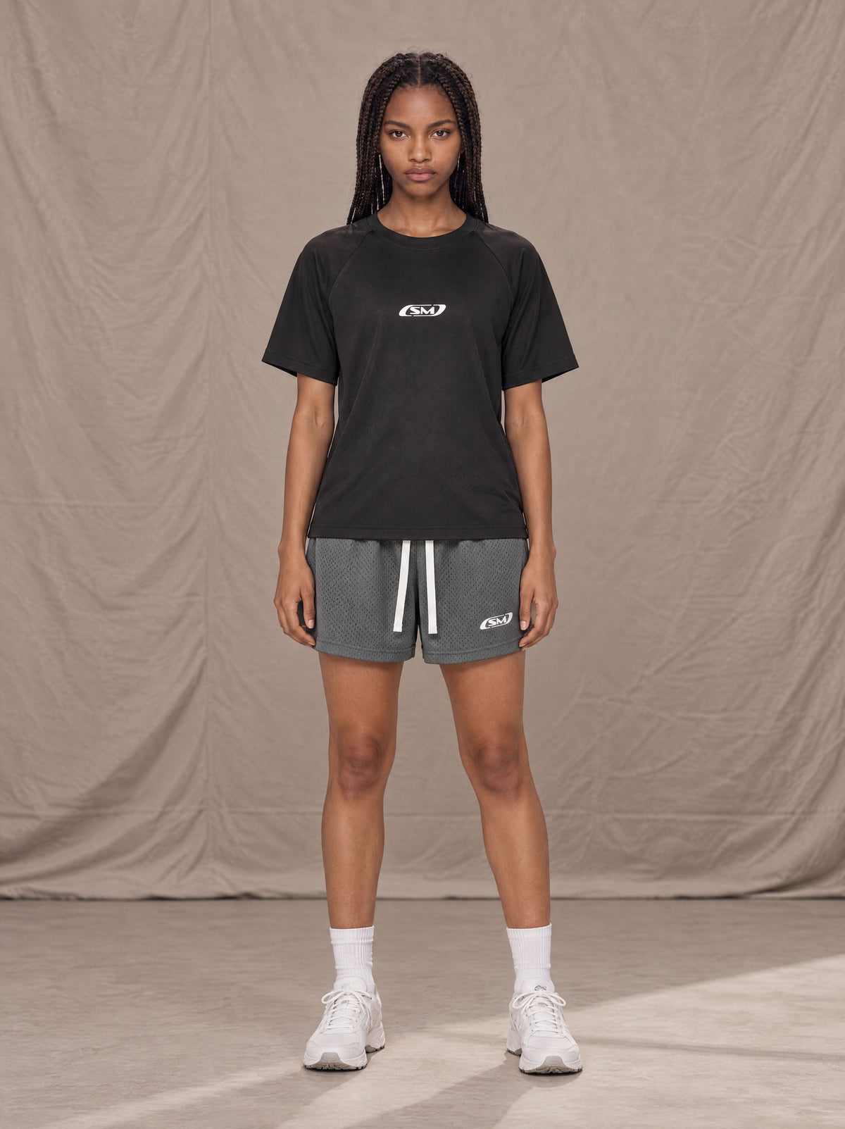 Model wearing the SM Motion Mesh Shorts in Ashen Grey, front view.
