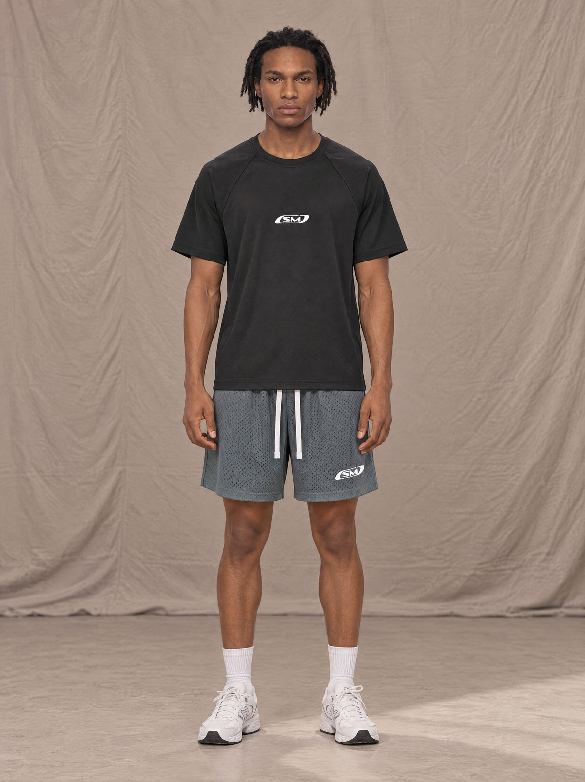 Model wearing the SM Motion Mesh Shorts in Ashen Grey, front view.