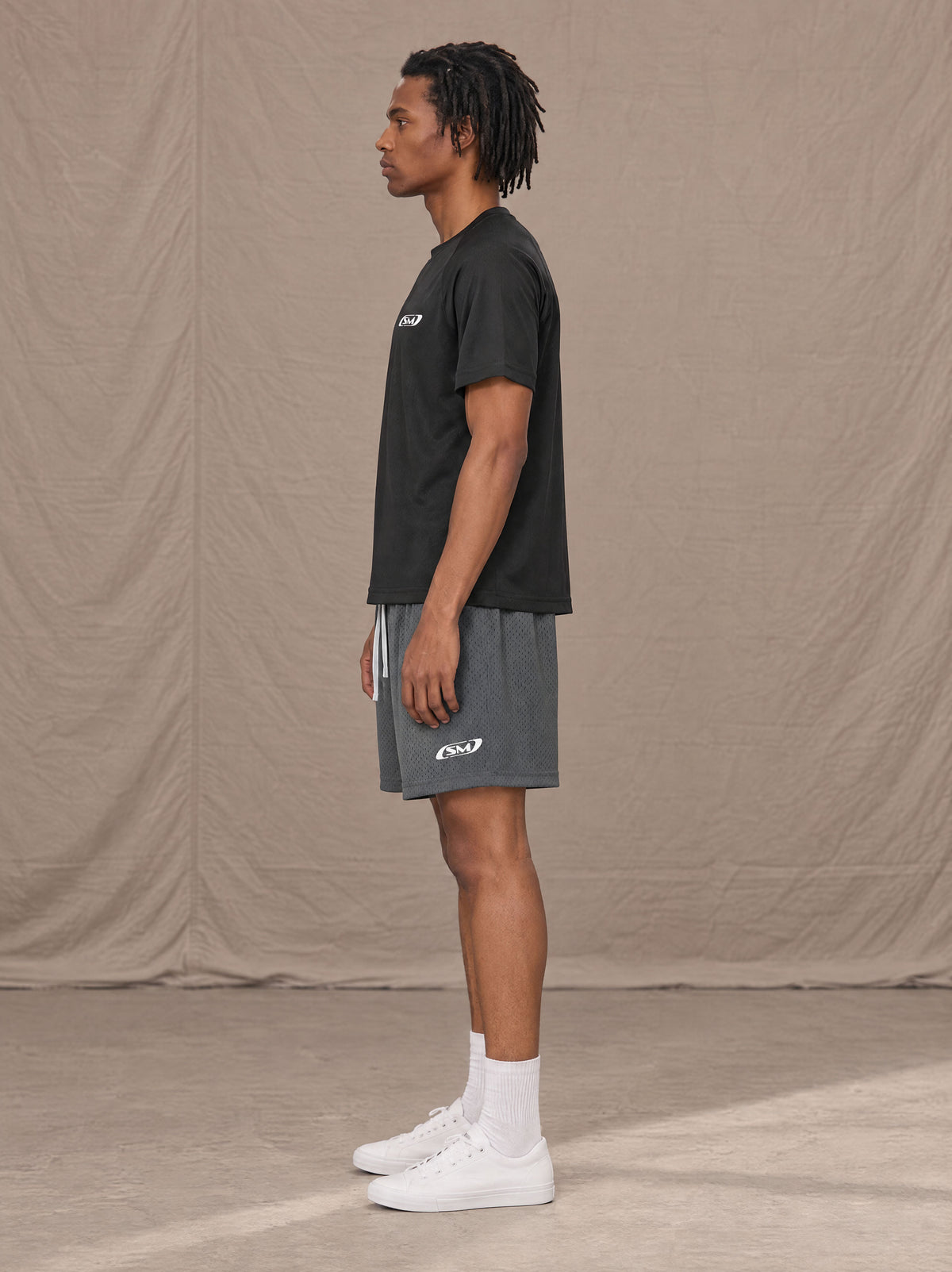 Model wearing the SM Motion Mesh Shorts in Ashen Grey, side profile.