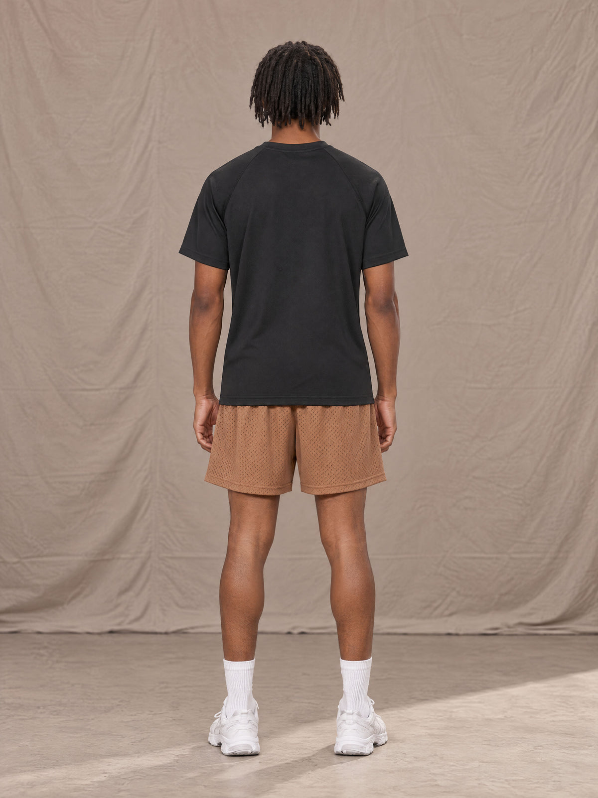 Model wearing the SM Motion Mesh Shorts in French Beige, rear view.