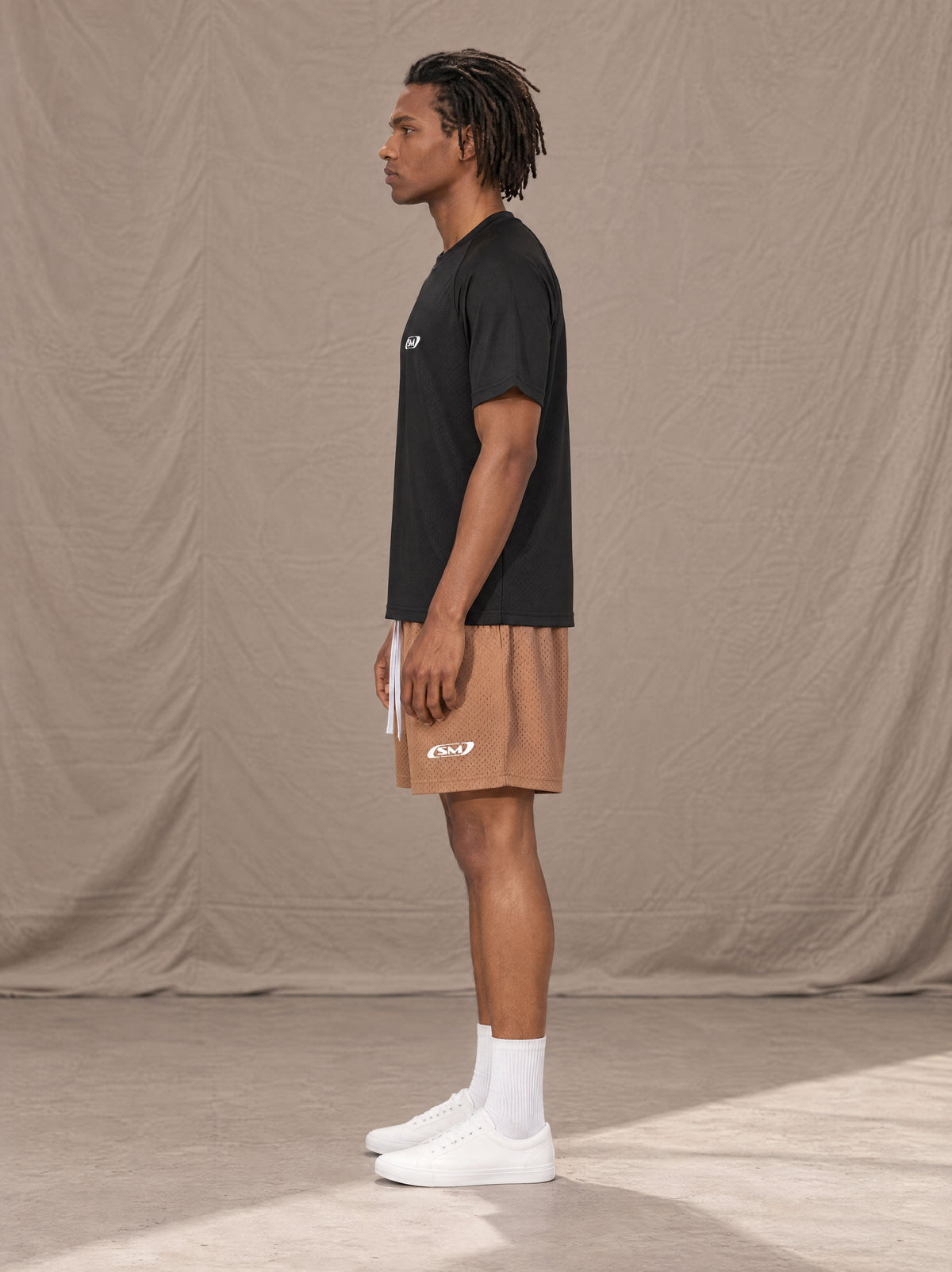 Model wearing the SM Motion Mesh Shorts in French Beige, side profile.