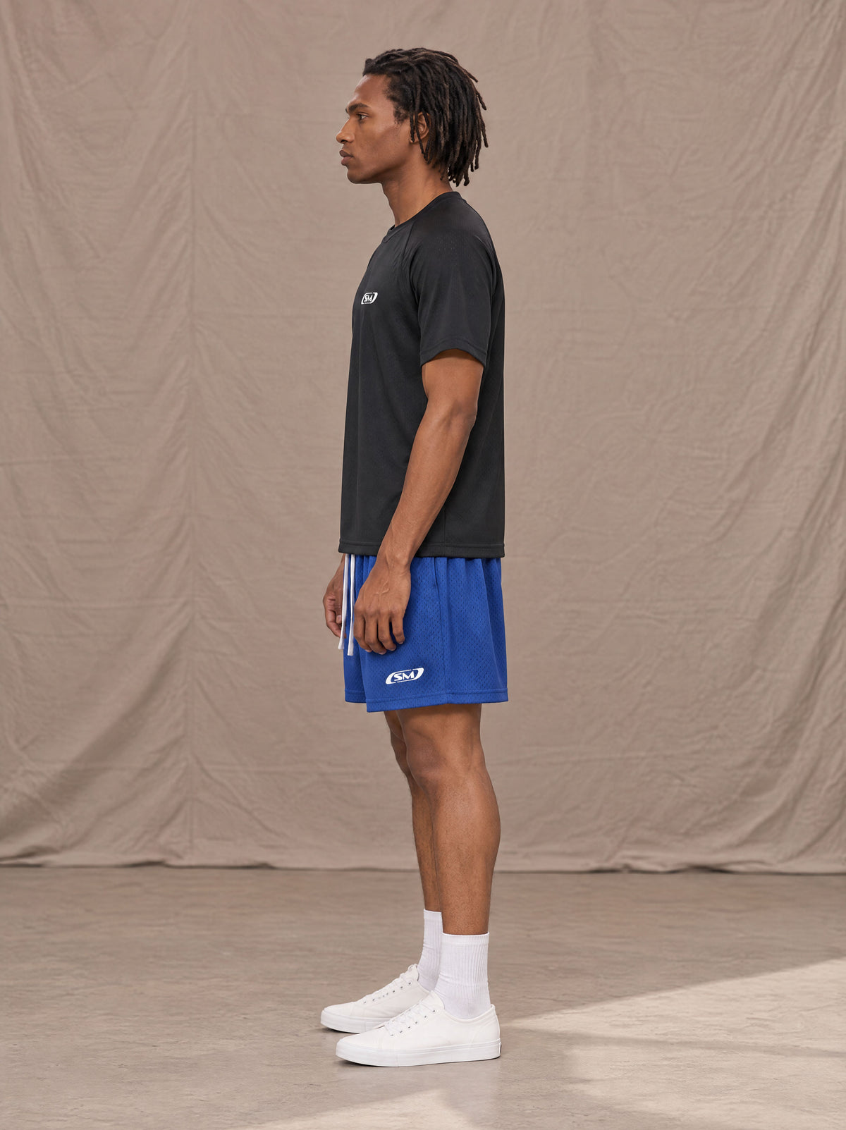 Model wearing the SM Motion Mesh Shorts in Klein Blue, side profile.