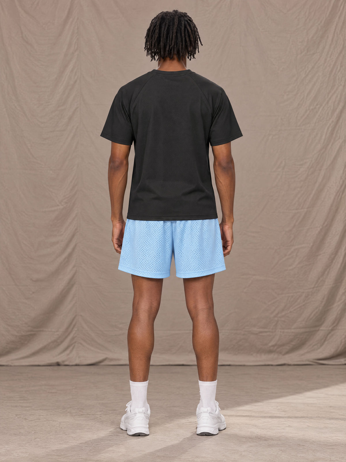 Model wearing the SM Motion Mesh Shorts in Sky Tint, rear view.