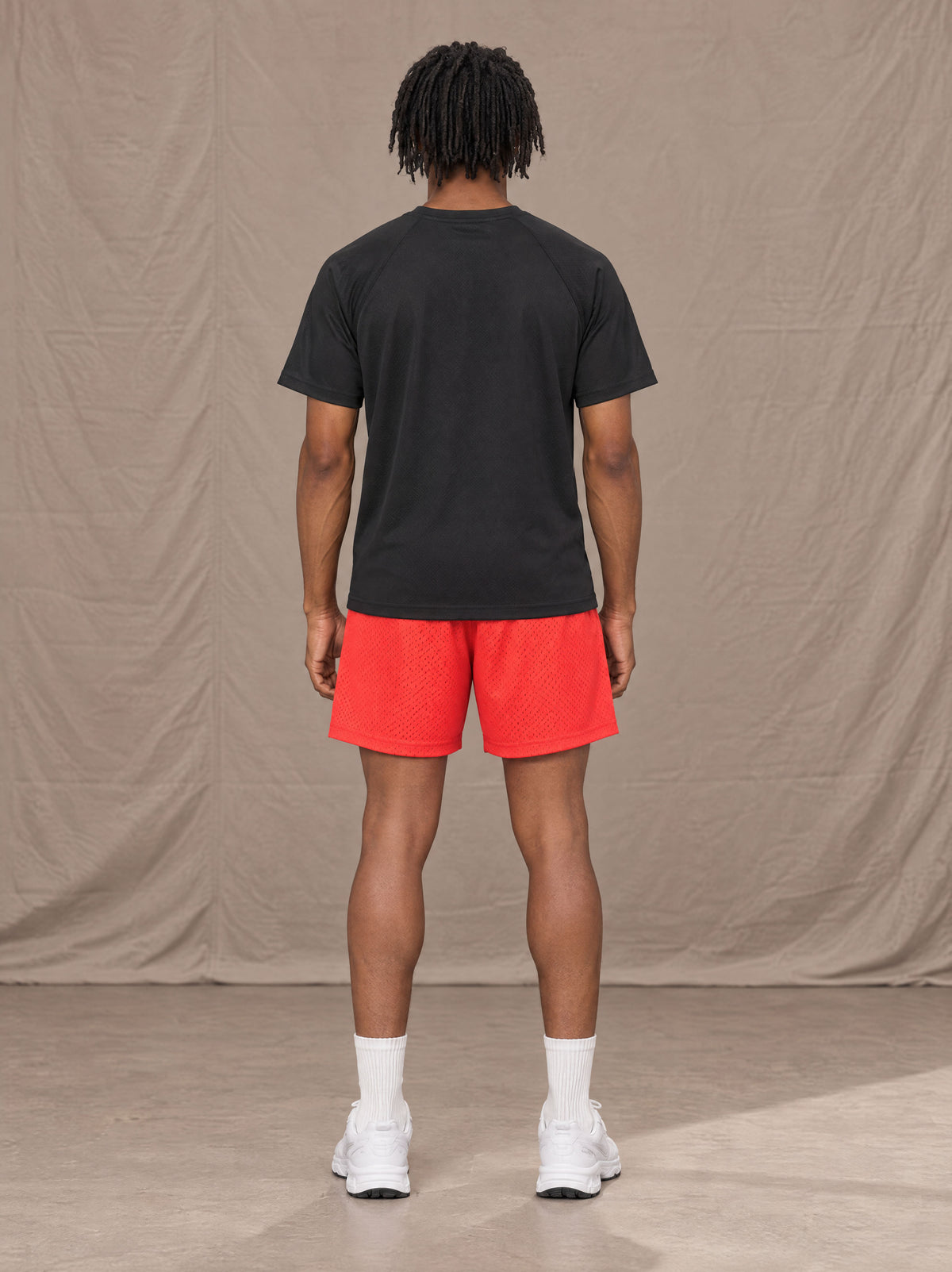 Model wearing the SM Motion Mesh Shorts in Watermelon Tint, rear view.