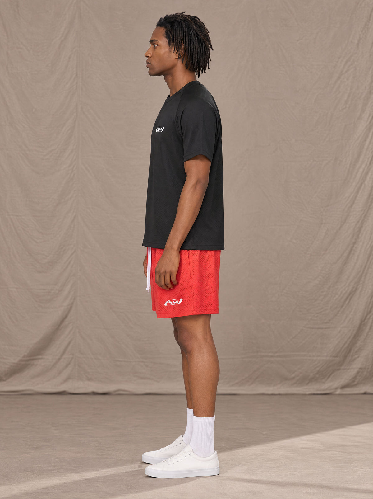 Model wearing the SM Motion Mesh Shorts in Watermelon Tint, side profile.