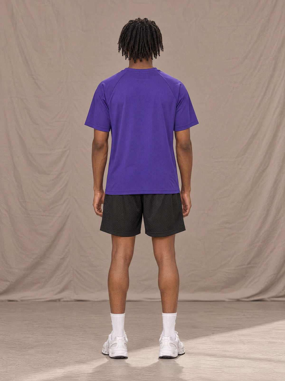 Model wearing the SM Motion Mesh T-shirt in Rich Violet, rear view.