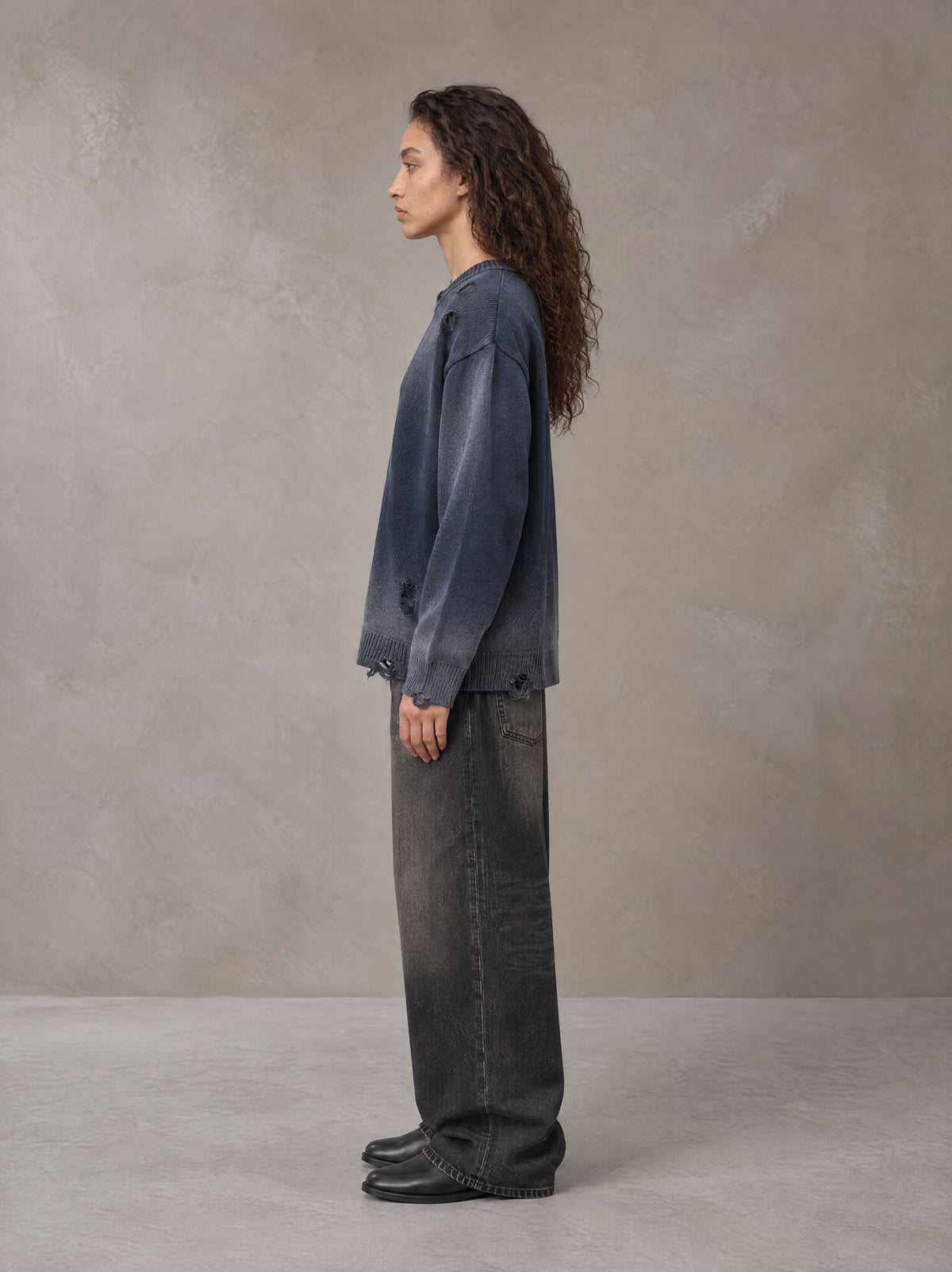 Model wearing the SM Sig. Washed Distress Knit Sweater in Oxford Navy, side profile.