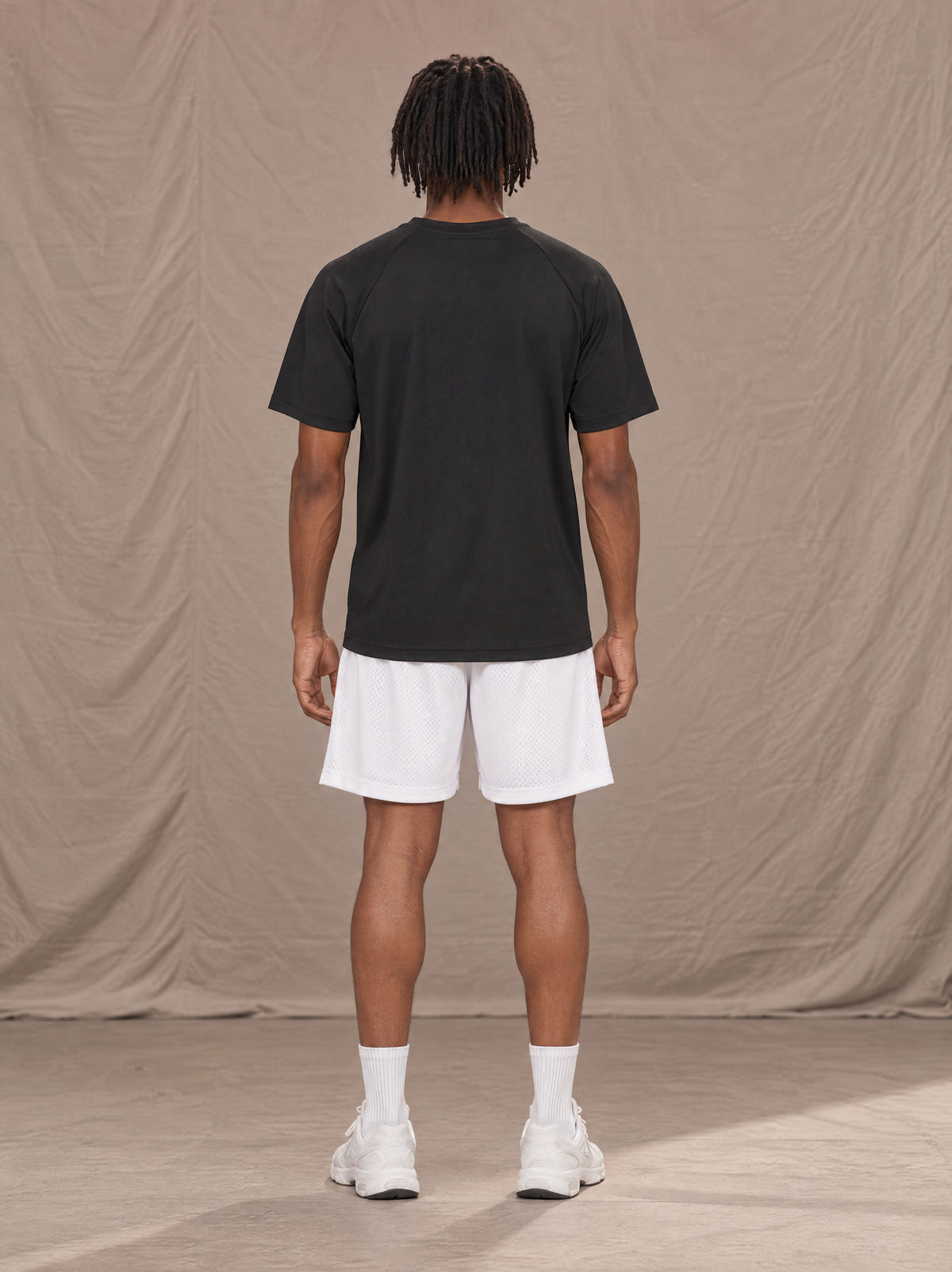 Model wearing the SM Motion Mesh Shorts in Lucent White, rear view.