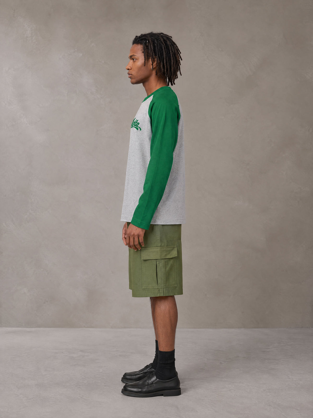 Model wearing SM Retro Raglan Long-Sleeve T-shirt in Heather Grey, side profile.