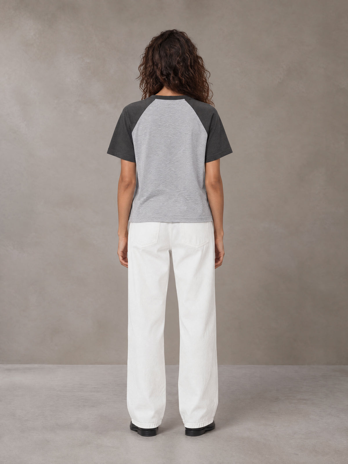 Model wearing SM Retro Raglan T-shirt in Deep Charcoal, rear view.