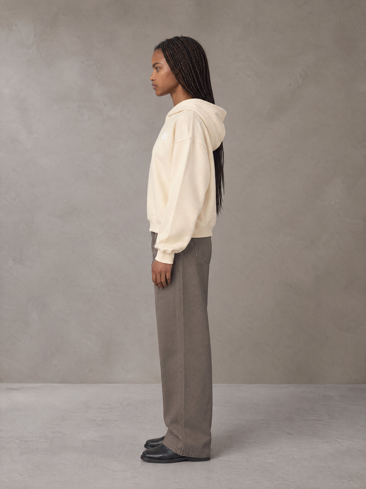 Model wearing SM Sig. Boxy Hoodie in Apricot Tint, side profile.